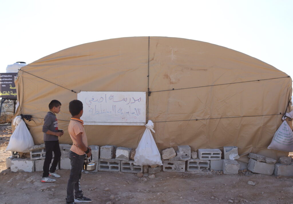 Due bambini davanti alla tenda che fungeva da scuola